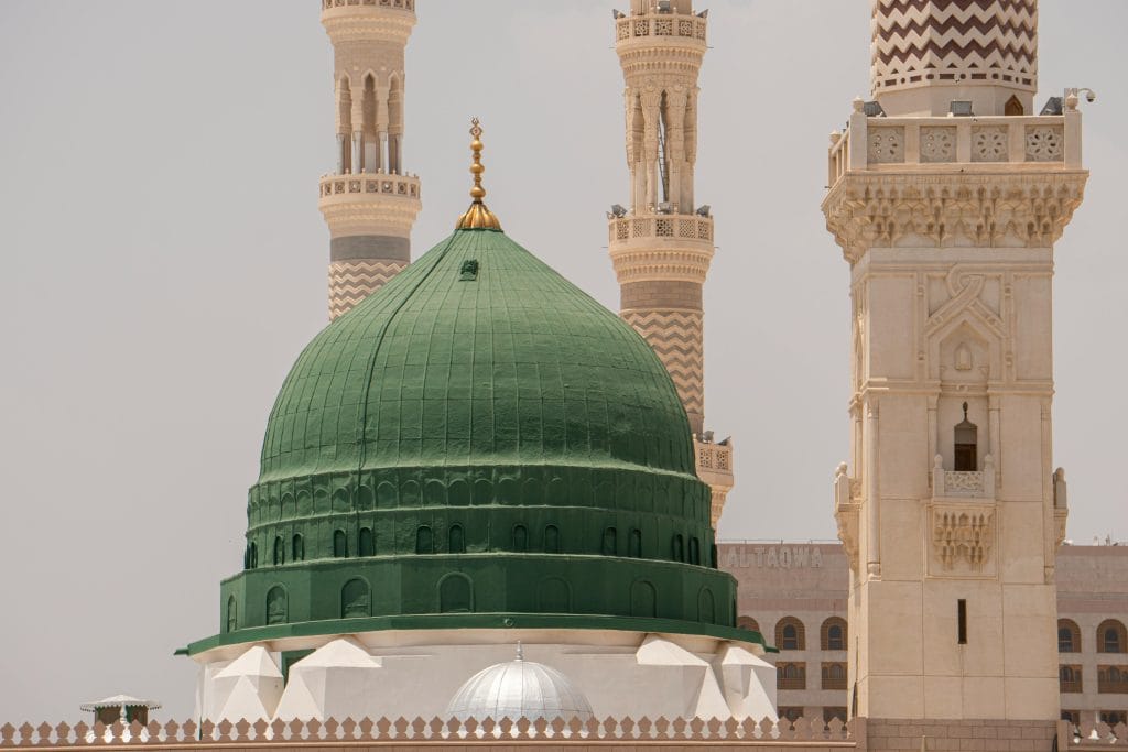 The iconic Green Dome of Al-Masjid an-Nabawi in Medina, Saudi Arabia, with surrounding minarets.